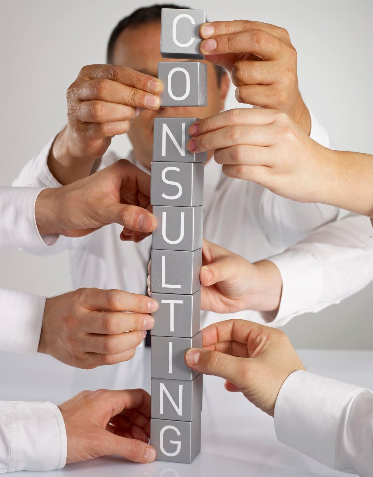 Hands stacking blocks that spell CONSULTING