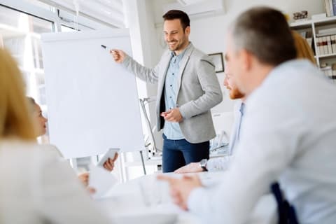 A consultant presenting at a whiteboard to colleagues